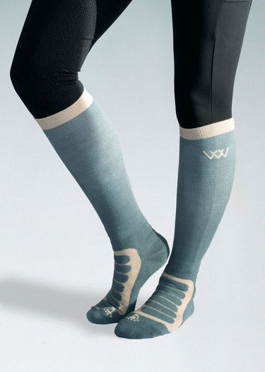 Teal knee-high socks with beige accents worn by a person on a light gray background