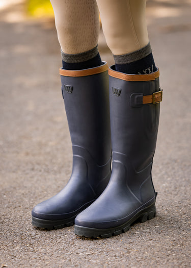 Blue rubber boots with brown trim worn by a person  