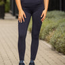 Woman in pink polo shirt and dark pants standing on a paved path with greenery in the background